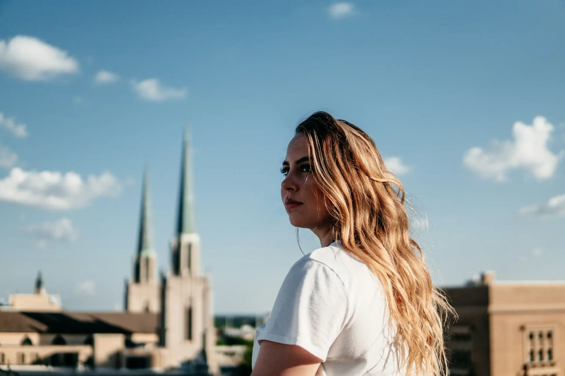 woman in white t-shirt standing on the street during daytime